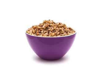 Dry buckwheat in purple ceramic bowl isolated on white