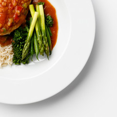 Corner of a plate of Asparagus and Broccoli on a white plate, and a tomato sause.