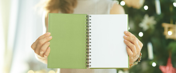 Closeup on woman showing green notebook with open blank page
