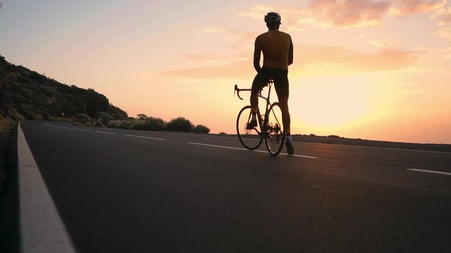 Man cyclist in a yellow t-shirt in the mountains watching the sunset. Resting after a workout, iron man