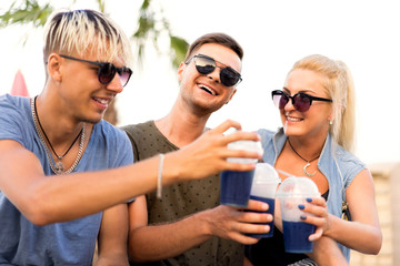 three friends on the beach drinking cocktails fun