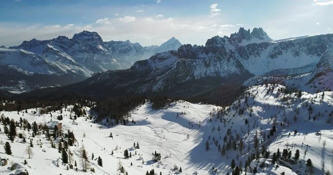 Forward aerial to snowy alpine valley with woods forest at Cinque Torri.Sunny sunset or sunrise,sunny day,cloudy sky.Winter Dolomites Italian Alps mountains outdoor nature establisher.4k drone flight