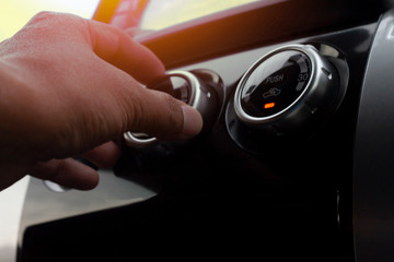 Hand of man Spin button of air condition in car.