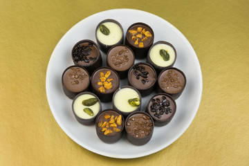 Chocolate candy on a white plate. Sweet beautiful candy lying on a plate on a bright color background.