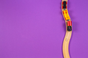 Toy train and wooden rails on purple violet background