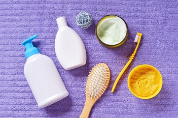 Flat lay toiletries set. Liquid soap package, shampoo bottle, wooden hairbrush, body cream, toothbrush and facial scrub. Top view bath products