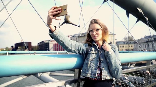Woman taking photo with cellphone on the bridge in the city, super slow motion
