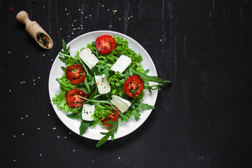 salad - arugula, cheese, tomatoes, lettuce and sesame (Healthy salad from fresh vegetables). Vegan food. Flat lay. Diet menu. Top view