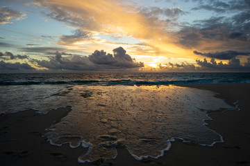 Beautiful sunset at the beach. Cloudy day witn a lot of reflections on the water
