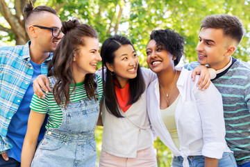 people, friendship and international concept - group of happy friends hugging in park