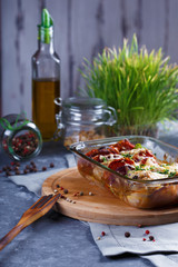 Chicken Casserole of Tomatoes, Onions, Cheese and Spices Menu and Restaurant Concept On Gray Background On the Kitchen Table with Dining Accessories