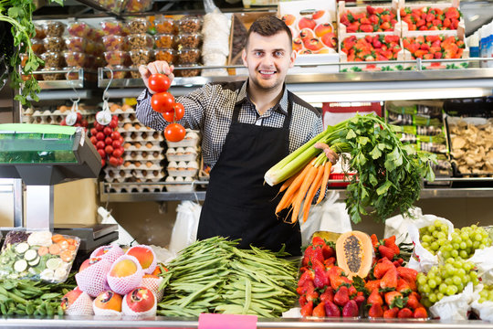 friendly man seller showing assortment of grocery shop