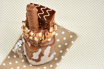 Chocolate extreme milkshake with brownie cake, chocolate paste and sweets. Crazy freakshake food trend. Copy space