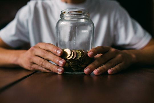 Crop man holding jar with coins