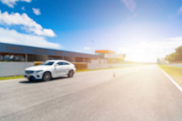 Fototapeta na wymiar Abstract blur and bokeh. White Luxury car in racetrack and speed racing back ground clear sky. Sunlight and flare concept.