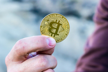 male miner’s hand holds gold coin bitcoin