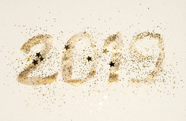 2019, New Year symbol hand written with golden paint with glitter and glittering stars in vintage nostalgic colors