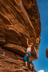 Girl Climber practicing bouldering on a beautiful red rock in Canyonlands Utah USA