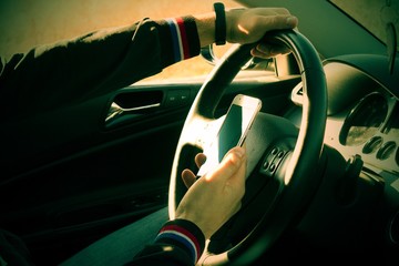 A IRRESPONSIBLE man driving a car with a MOBILE PHONE in his hand.A man holds a driving wheel and a...
