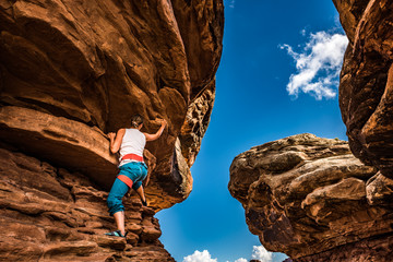Girl Climber practicing bouldering on a beautiful red rock in Canyonlands Utah USA