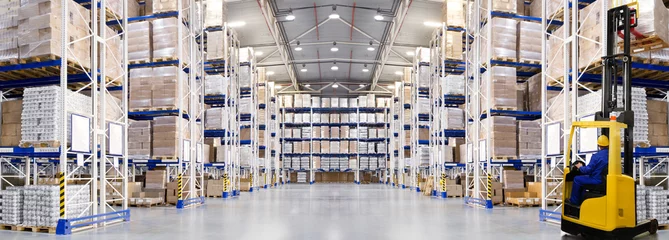 Photo sur Plexiglas Bâtiment industriel Immense entrepôt de distribution avec étagères hautes et chariot élévateur