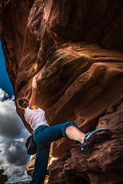 Girl Climber practicing bouldering on a beautiful red rock in Canyonlands Utah USA
