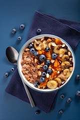 chocolate oatmeal porridge with blueberry, nuts, banana, dried apricot for healthy breakfast. Top view © Olga Miltsova
