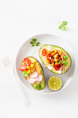avocado boats stuffed with hummus, tomatoes, radish, roasted chickpea