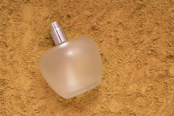 glass bottle of perfume is on the sand