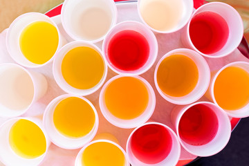 Mix of children drinks in white plastic cups from above.