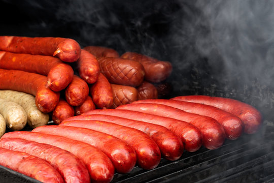 Bratwurst sausages on smoky cast iron griddle.