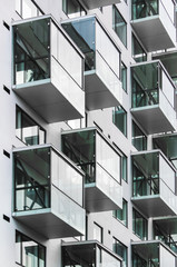 Wall of gray building with glass cubic balconies. Modern architecture