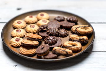 shortbread butter cookies with chocolate and plum jam on a white wooden table