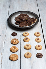shortbread butter cookies with chocolate and plum jam on a white wooden table