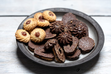 shortbread butter cookies with chocolate and plum jam on a white wooden table
