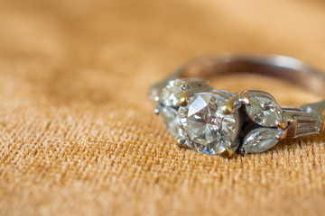 Jewelry diamond ring on golden fabric background close up