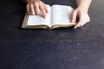 Woman Studying Her Bible on a Dark Table