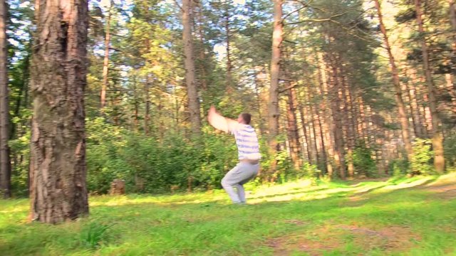 young guy jumps and does a flip in the forest