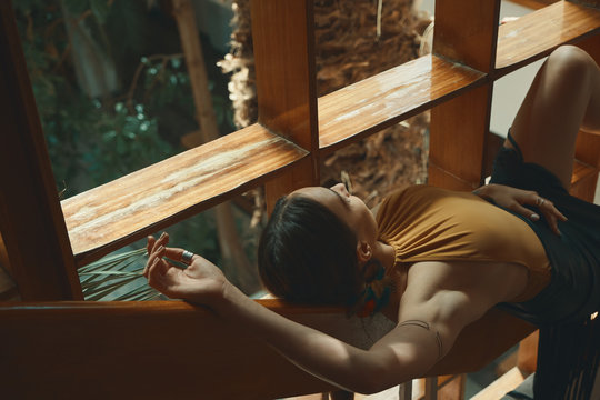 Preety Woman Relaxing while lying on a wooden stair railing near