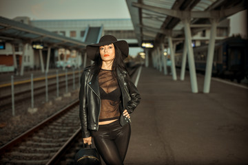 Fototapeta na wymiar Young sexy woman dressed in black posing on a train station pier.
