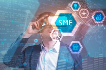 Obraz premium Business, Technology, Internet and network concept. Young businessman working in virtual reality glasses sees the inscription: SME