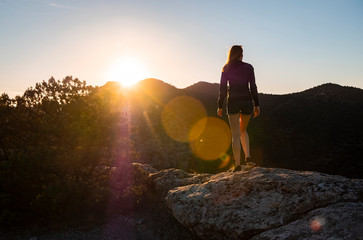 Girl in the mountains on top at sunset or dawn