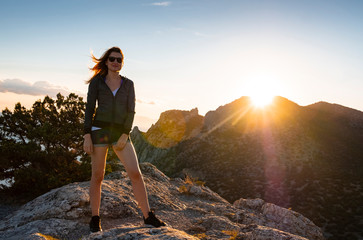 Girl in the mountains on top at sunset or dawn