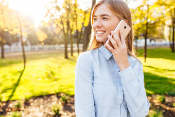 young happy beautiful girl walking in the park and talking on the phone