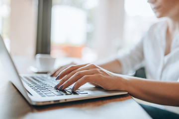 Closeup female hands typing on laptop keyboard.