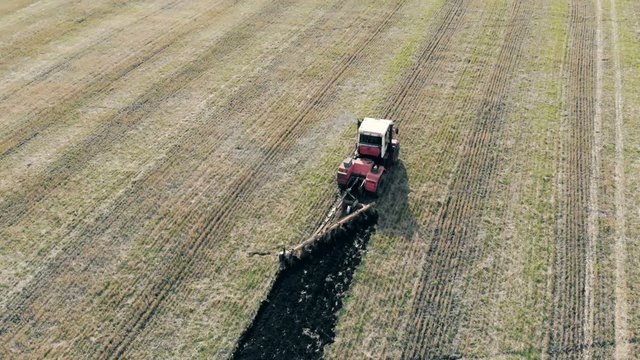 Aerial view of a modern tractor plowing dry field.