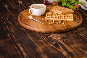 fresh belgian waffles, tasty jam and latte coffee on a wooden background. top view.