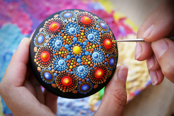 Drawing with a brush a mandala on a stone
