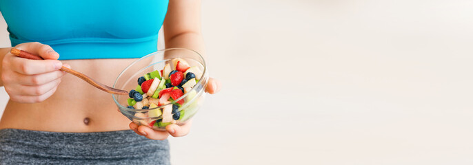 Young woman eating a healthy fruit salad after workout. Fitness and healthy lifestyle concept.