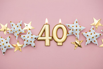 Number 40 gold candle and stars on a pastel pink background